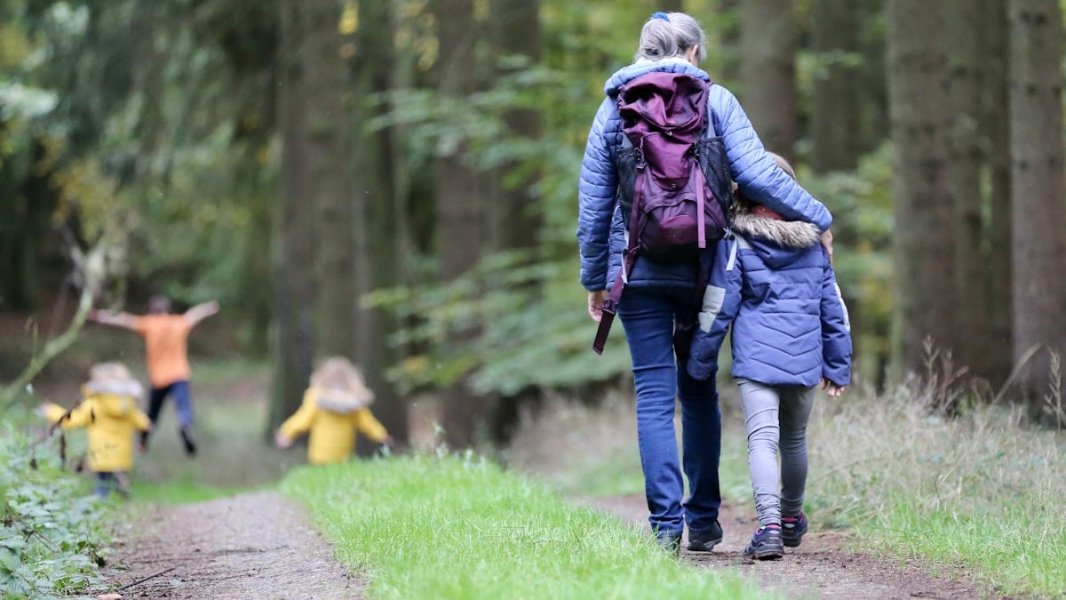 Grandmother with grandchildren hiking in a forest.